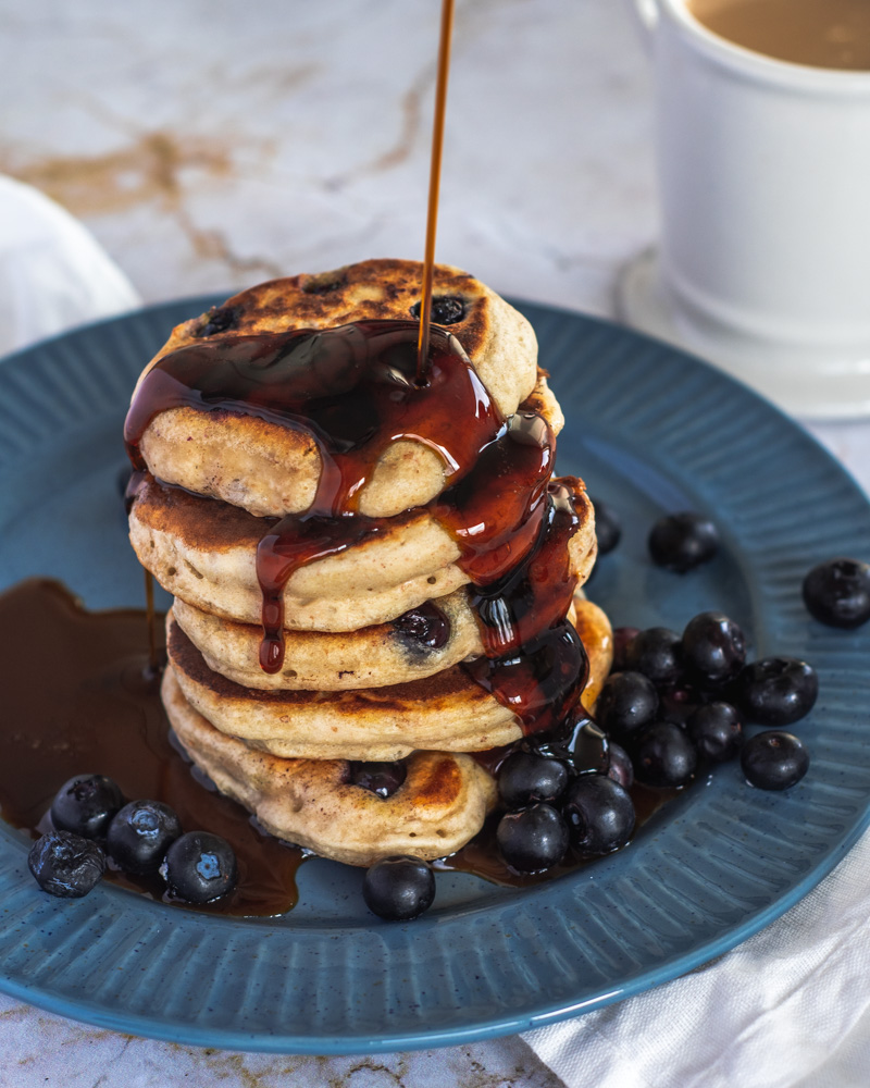 Sourdough pancake stacked high with maple syrup and blueberries.